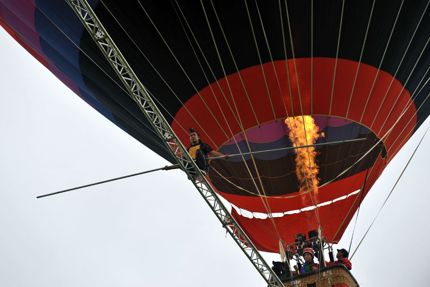 Mardi 30 juillet au Karst de Shilin, dans la province du Yunnan en Chine, l'acrobate ouïgur Esqer marche sur une poutre fixée entre deux montgolfières. 