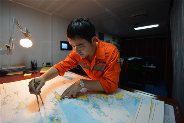 Un marin traçant sur une carte la route du navire de sauvetage, le Donghaijiu 101, le 30 juillet 2013. [Photo/Xinhua]