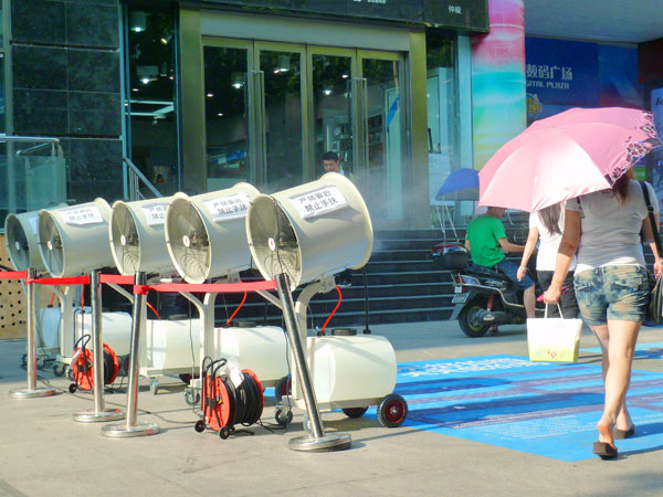 Cinq ventilateurs de refroidissement par pulvérisation sont opérationnels devant un magasin de Nanjing pour rafraîchir les clients et les passants, la province du Jiangsu dans l'est de la Chine, le 29 Juillet 2013.