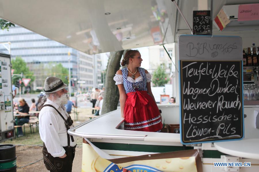 Une vendeuse en costume traditionnel lors du 17e Festival de la Bière de Berlin, sur l'Avenue Karl Marx à Berlin, en Allemagne, le 4 août 2013. Quelque 330 brasseries venant de 86 pays et régions sont venues à Berlin pour ce Festival international de la Bière qui débute depuis vendredi et durera trois jours. (Xinhua/Zhang Fan)