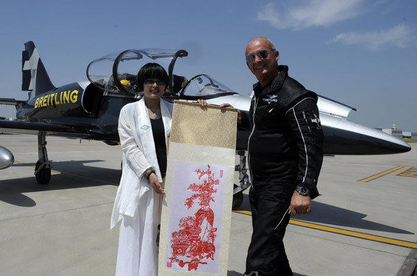 Un membre du Breitling Jet Team, reçoit un présent lui souhaitant la bienvenue, après son arrivée à l'aéroport international de Yinchuan Hedong à Yinchuan, capitale du Ningxia Hui région autonome de la Chine du Nord, le 11 août 2013.