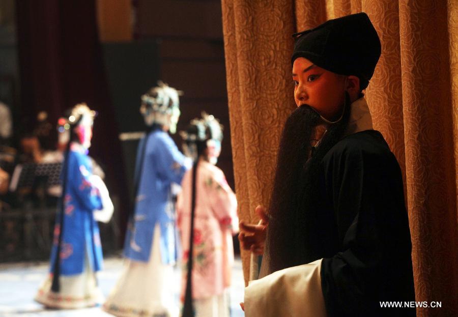 Le 12 août 2013 au Grand Théâtre de Chine à Tianjin, Li Yunruo (1er à droite), un jeune acteur amateur de l'opéra de Pékin, attend son tour derrière le rideau. (Photo : Xinhua/Liu Dongyue)