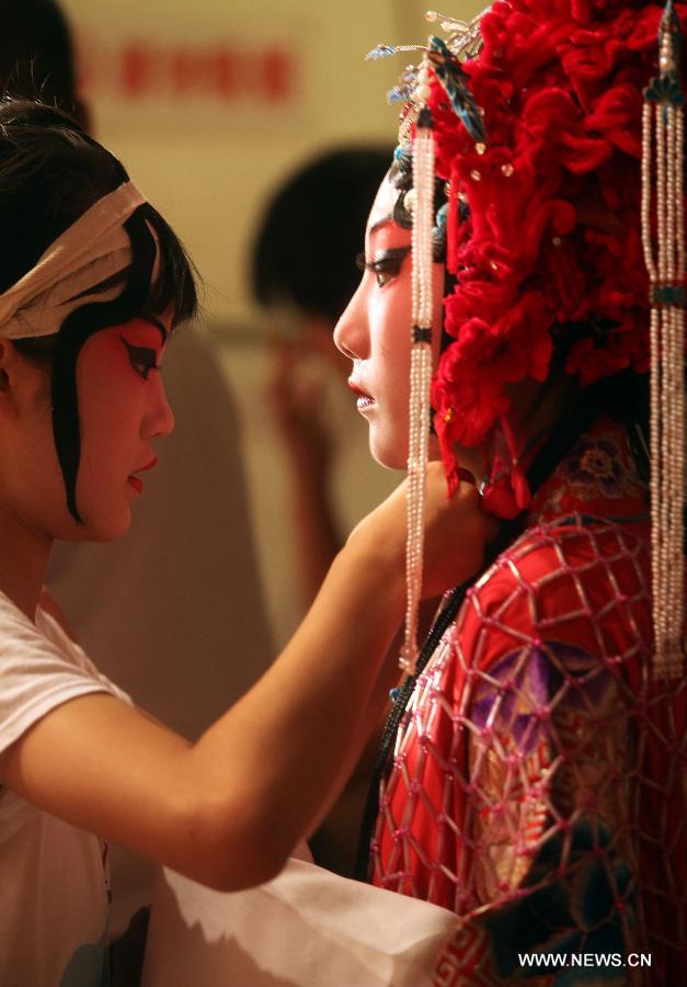 Le 12 août 2013 au Grand Théâtre de Chine à Tianjin en Chine, Cao Wenjing (à droite), une actrice en herbe de l'opéra de Beijing se prépare en coulisse. (Photo : Xinhua/Liu Dongyue)