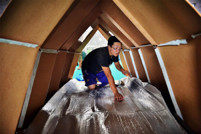 Un étudiant de l'école de génie mécanique de l'Université de Tianjin dispose un tampon étanche à l'humidité sous une tente faite en papier dans le gymnase de l'université de la municipalité de Tianjin, au nord de la Chine, le 27 août 2013.