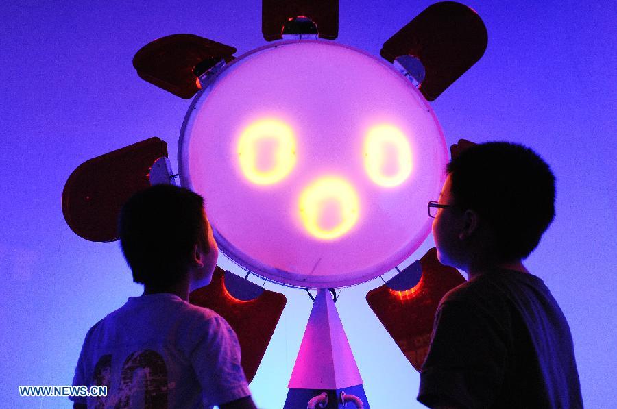 Deux enfants devant un dispositif pouvant prédire les jours ensoleillés et pluvieux au cours de l'édition 2013 de l'Exposition internationale «Science et Art» de Shanghai, en Chine orientale, le 28 août 2013. l'événement qui va durer six jours a débuté mercredi au Shanghai Exhibition Center.