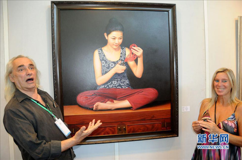 Jeudi 29 août, lors de la 16e Exposition internationale d'Art de Beijing, deux visiteurs étrangers posent devant une oeuvre du peintre chinois Li Hongyu. (Photo : Xinhua)