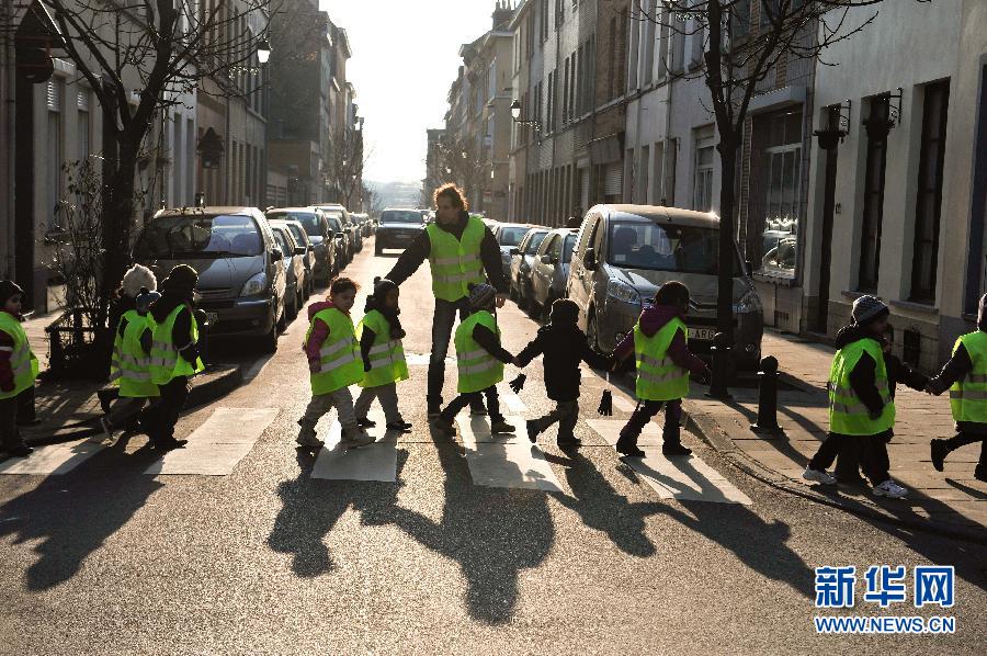 Le 21 février 2013 à Bruxelles, la capitale belge, des jeunes enfants traversent la rue, ils sont encadrés par un enseignant de la maternelle. (Photo : Xinhua /Ye Pingfan)