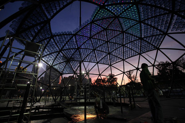 Réalisation d'une sculpture contenant 7000 bonbonnes d'eau recyclées avec des lumières LED, mesurant 20 mètres de diamètre et 10 mètres de hauteur, au coucher du soleil du parc Victoria de Hong Kong, le 10 septembre 2013.