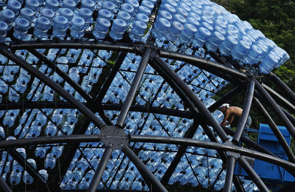 Un ouvrier à la tâche sur une sculpture contenant 7000 bonbonnes d'eau recyclées avec des lumières LED, mesurant 20 mètres de diamètre et 10 mètres de hauteur, dans le parc Victoria de Hong Kong, le 10 septembre 2013.