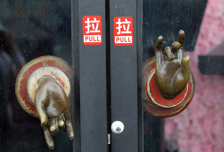 Une porte de bar avec des poignées en forme de mains de Bouddha dans la rue des bars de Shichahai. [Photo Zou Hong / China Daily]