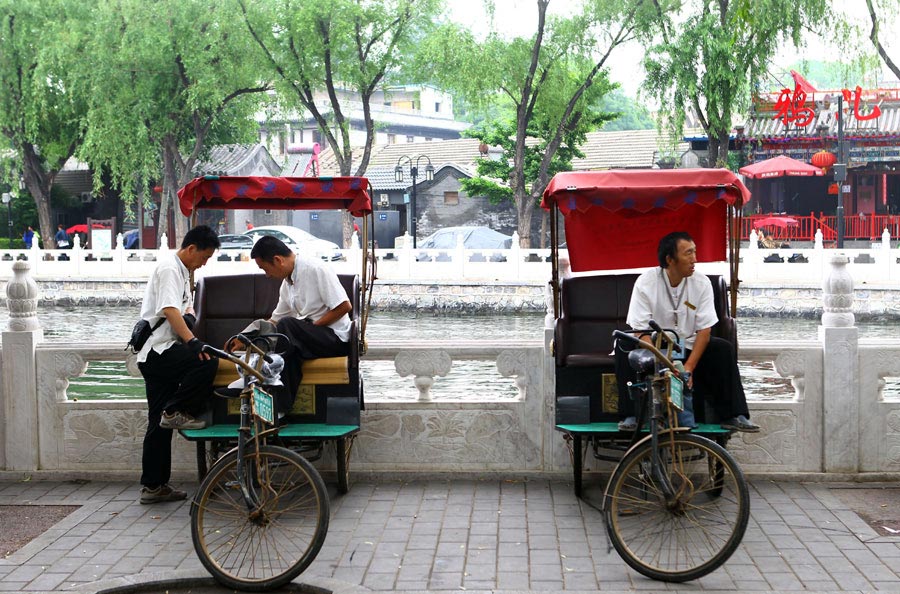 Des conducteurs de vélo-pousse attendent les clients à proximité du lac Houhai. [Photo Zou Hong / China Daily]
