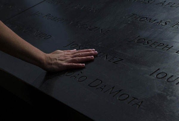 Une femme pose sa main sur des noms du bassin du nord au Mémorial du 11 septembre, à New York, le 9 septembre 2013. [Photo / agences]