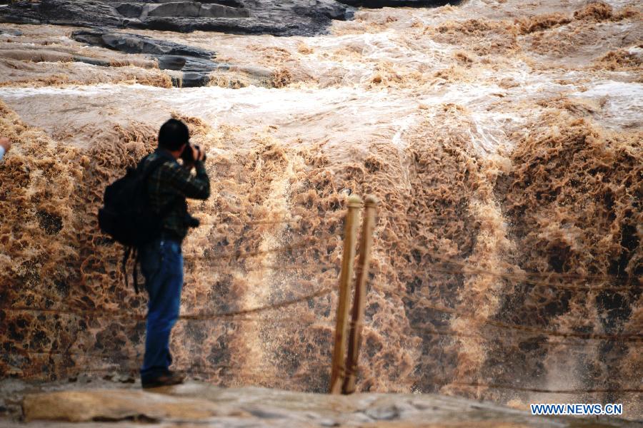 Un touriste prend des clichés de la cascade Hukou du fleuve Jaune, située dans le comté de Jixian, la province chinoise du Shanxi (nord du pays), le 12 septembre 2013. [Photo/Xinhua]