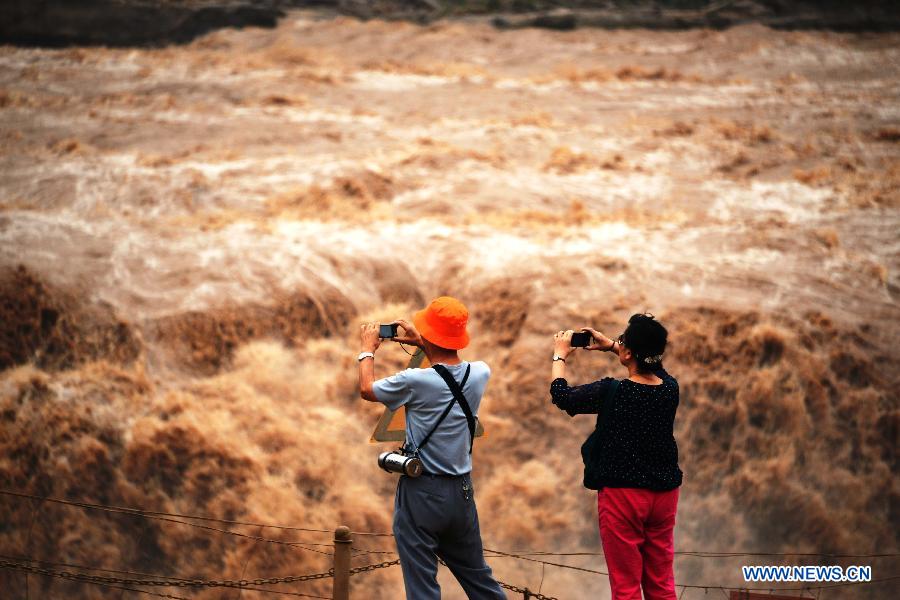 Des touristes prennent des photos de la cascade Hukou du fleuve Jaune, située dans le comté de Jixian, la province du Shanxi (nord de la Chine), le 12 septembre 2013. [Photo/Xinhua]
