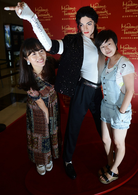 Deux fans aux côtés de la statue en cire représentant la pop star disparue Michael Jackson, destinée à la future branche du musée de cire de Madame Tussauds à Wuhan, la province du Hubei, le 15 septembre 2013.[Photo: Zhou Chao/Asianewsphoto]