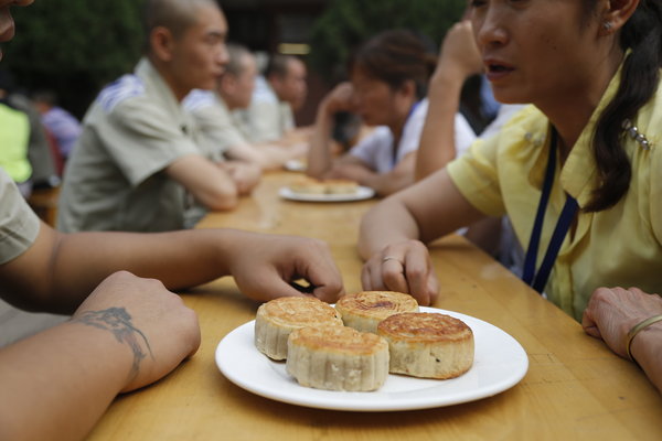 Des détenus et les membres de leur famille reçoivent des gâteaux de lune à la prison de Sanmenxia, à quelques jours de la Fête de la Mi-automne, à Sanmenxia, dans la Province du Henan, le 17 septembre 2013. [Photo / CFP]