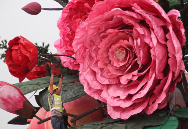 Un travailleur ajuste des fleurs artificielles sur la place Tian'anmen pour célébrer la Fête Nationale, qui aura lieu le 1er octobre à Beijing, le 22 septembre 2013. [Photo / Asianewsphoto]