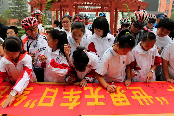 Les étudiants signent leurs noms sur une bannière pour promouvoir la Journée mondiale sans voiture dans un club de vélo de la ville de Xingtai, la province du Hebei (nord de la Chine), le 22 septembre. [Photo/Xinhua]