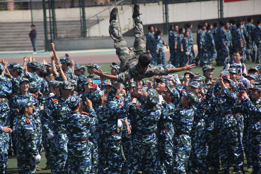 Les élèves et leur instructeur célèbrent la fin de la formation militaire des nouveaux étudiants de l'Université du Shandong, à Jinan, dans la Province du Shandong en Chine de l'Est, le 26 septembre 2013. [Photo Zheng Tao / Asianewsphoto]