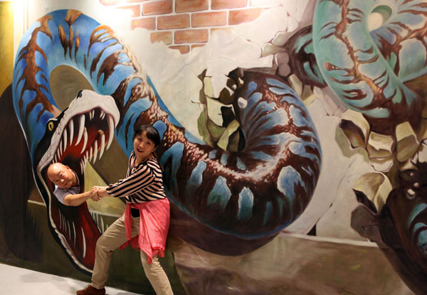 Deux visiteurs se prennent au jeu, devant un tableau 3D, lors d'une exposition d'art à Nanjing, la province chinoise du Jiangsu, le 7 octobre 2013. [Photo: Yu Hua/Asianewsphoto]
