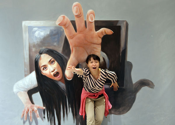 Une jeune chinoise prise dans l'action devant une oeuvre 3D, lors d'une une exposition d'art à Nanjing, la province chinoise du Jiangsu, le 7 octobre 2013. ces peintures en 3D, offre un spectacle saisissant, plus vrai que nature pour les nombreux visiteurs. [Photo: Yu Hua/Asianewsphoto]