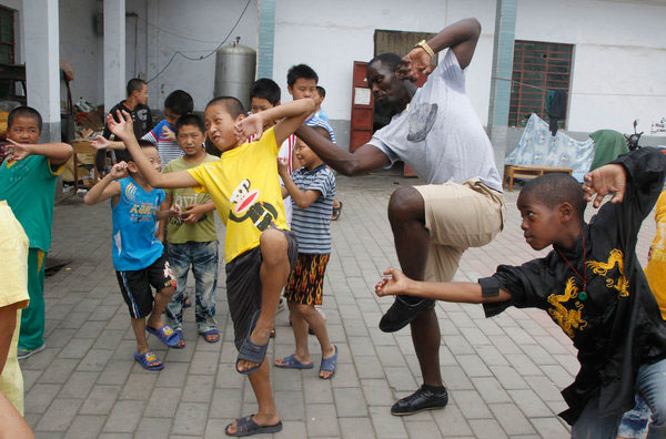 Un visiteur étranger joue avec des enfants dans un orphelinat fondé par l'institution, au temple de Shaolin de Dengfeng, la province du Henan, le 7 septembre 2013 .