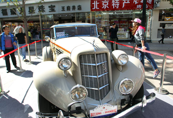 Les visiteurs prennent des photos d'une voiture de marque, lors d'une exposition de voitures anciennes dans la rue Wangfujing à Beijing, le 10 octobre. (Photo : Zou Hong/China Daily)