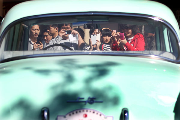 Des visiteurs prennent des photos d'une voiture de la marque Shanghai, lors d'une exposition de voitures anciennes dans la rue animée de Wangfujing à Beijing, le 10 octobre, où près de soixante voitures de renommée mondiale ont été exposées. L'exposition de douze jours se rendra à Tianjin, Shanghai et dans quatre provinces, dont le Hebei et Shandong. (Photo : Zou Hong/China Daily