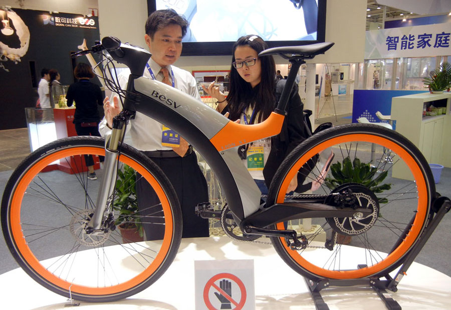 Un membre du personnel de l'exposition présente un vélo électrique intelligent à un visiteur lors de la 12e Exposition de fabricants de produits électroniques de Chine , qui se tient pendant cinq jours à Suzhou, dans la Province du Jiangsu, mercredi.
