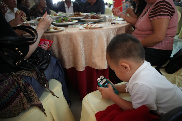 Un garçon joue avec un smartphone lors d'un banquet de mariage à Shenyang, le 8 septembre 2013.