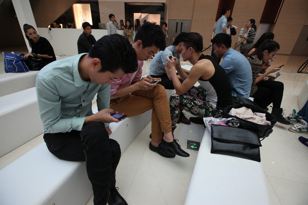 Des modèles s'amusent avec leurs téléphones, pendant la pause d'un spectacle à Shenyang, le 29 septembre 2013.