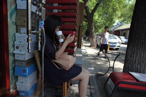 Une femme regarde son téléphone portable devant une tasse de café à Beijing, le 1er septembre 2013.