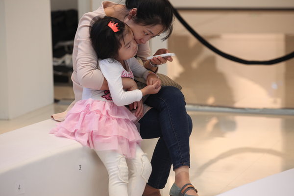 A Shenyang, une femme occupée avec son mobile, tout en tenant sa fille, le 30 septembre 2013.