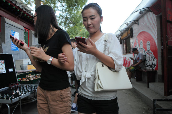 Deux jeunes chinoises occupées à consulter le portable tout en marchant dans une rue à Beijing, le 30 août 2013.