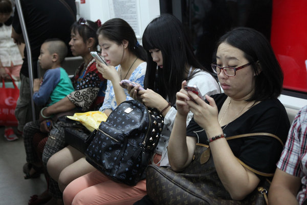 Des personnes regardant leurs mobiles dans le métro de Beijing, le 30 août 2013.