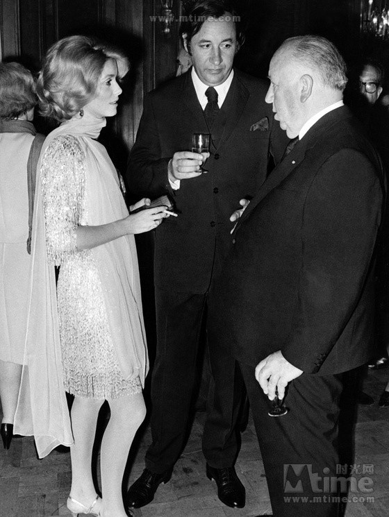 Catherine Deneuve, le réalisateur Alfred Hitchcock et l'acteur français Philippe Noiret lors d'une soirée. 