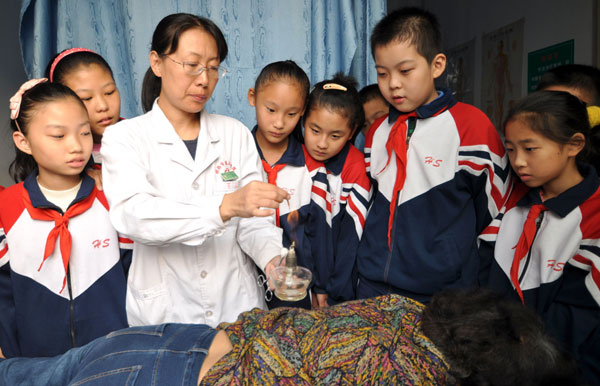 Un praticien de la MTC montre aux élèves un traitement à l'acupuncture, le 21 octobre 2013 à Handan, dans la province du Hebei. [Photo Hao Qunying / Asianewsphoto]