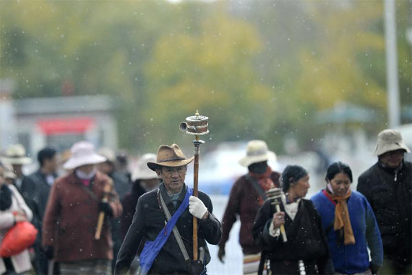 Des gens marchent dans la neige à Lhassa, capitale de la région autonome du Tibet, dans le sud de la Chine, le 28 octobre 2013. Des chutes de neige ont touché de nombreuses régions au Tibet lundi. [Photo/Xinhua ]