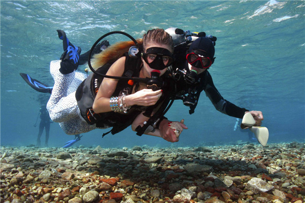 Un assistant accompagne un modèle alors qu'elle plonge vers l'emplacement d'une séance de photos sous-marine en Mer Rouge, au large de la ville balnéaire d'Eilat, le 23 octobre 2013. [Photo / agences]