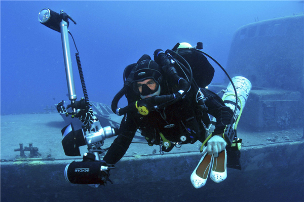 Le photographe israélien Johannes Felten tient une paire de chaussures alors qu'il plonge vers l'emplacement d'une séance de photos sous-marines en Mer Rouge, au large de la ville balnéaire d'Eilat, le 23 octobre 2013. [Photo / agences]