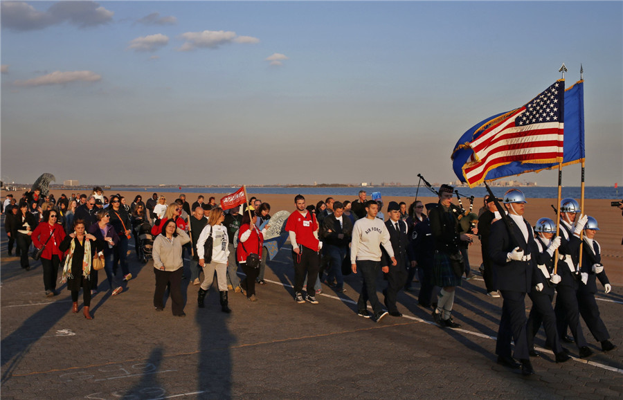 Des habitants de Staten Island marchent ensemble derrière une garde du drapeau sur la promenade de la rive sud de l'île à New York pour commémorer le premier anniversaire de l'ouragan Sandy, dans l'arrondissement de Staten Island de la ville de New York, le 29 octobre 2013.