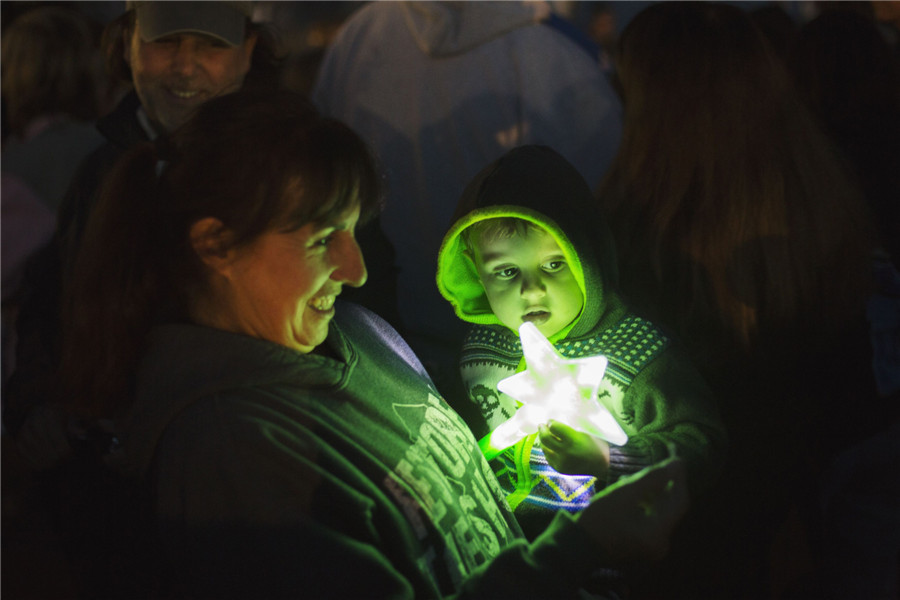 Une femme et son enfant tenant un jouet participent à une manifestation d'illumination de la côte pour le premier anniversaire de l'ouragan Sandy à Seaside Heights, dans le New Jersey, le 29 octobre 2013.