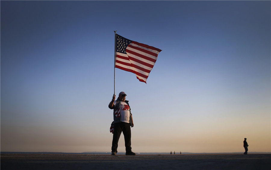 John Childs, qui a perdu sa maison dans le quartier de New Dorp Beach de Staten Island lors de l'ouragan Sandy tient un drapeau américain au bord de la plage sur la côte sud de l'île lors d'une manifestation destinée à commémorer le premier anniversaire de l'ouragan Sandy dans l'arrondissement de Staten Island de la ville de New York, le 29 octobre 2013.