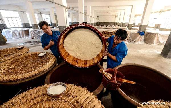 Des brasseurs remplissent des récipients en céramique géants avec du riz gluant cuit à la vapeur pour la fermentation lors du brassage d'hiver annuel à la distillerie de Shenyonghe à Shaoxing, province du Zhejiang, dans l'est de la Chine, le 30 octobre 2013.[Photo/Xinhua]