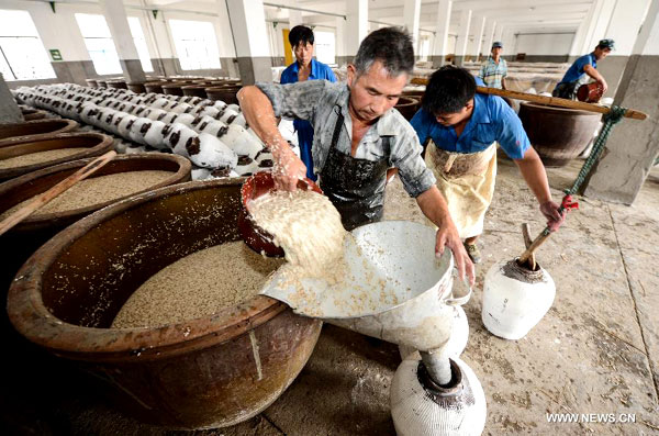 Des brasseurs remplissent des récipients en céramique avec du riz gluant fermenté lors du brassage d'hiver annuel à la distillerie de Shenyonghe à Shaoxing, province du Zhejiang, dans l'est de la Chine, le 30 octobre 2013.[Photo/Xinhua ]