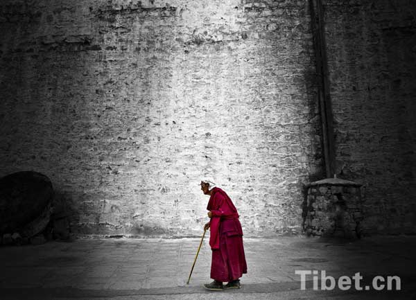 Un vieux moine tibétain marche seul dans le monastère Drupeng au Tibet.