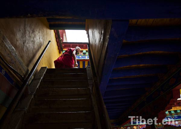 Un moine en robe pourpre en haut d'un escalier dans le monastère Drupeng au Tibet, l'un des six plus grands temples de la secte Gelugpa du bouddhisme tibétain.