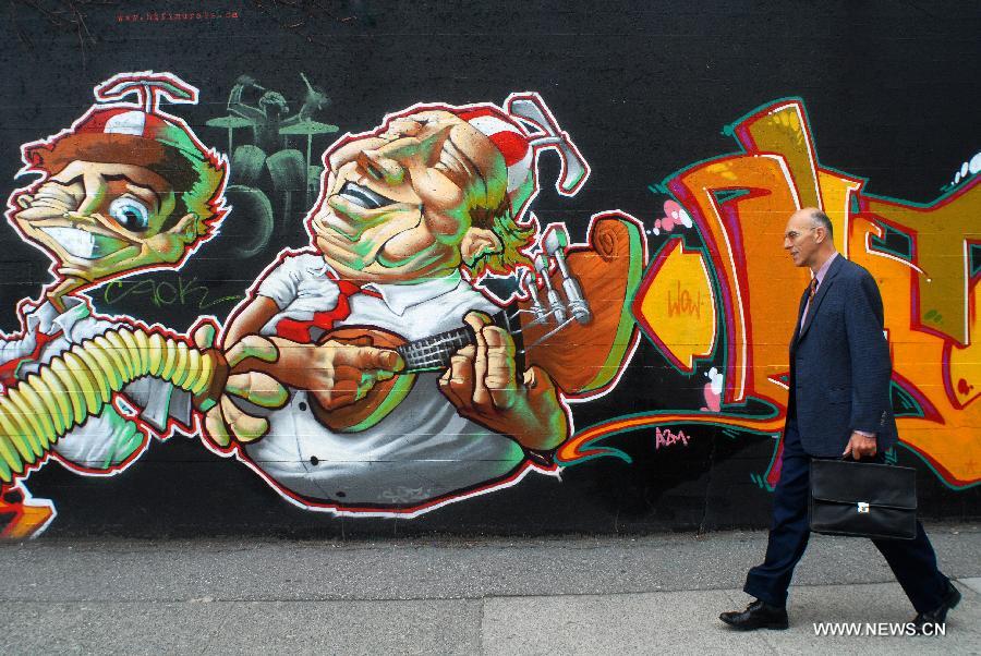 Un piéton passe devant un mur de graffiti à Vancouver, au Canada, le 9 mai 2008.(Xinhua/Sergei Bachlakov)
