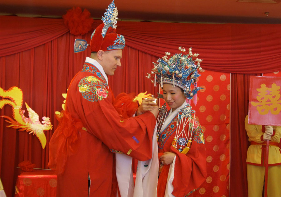 Une mariée chinoise et son époux américain boivent du vin ensemble lors d'une cérémonie traditionnelle dans la Province du Jiangxi, en 2008. [Photo / Xinhua]