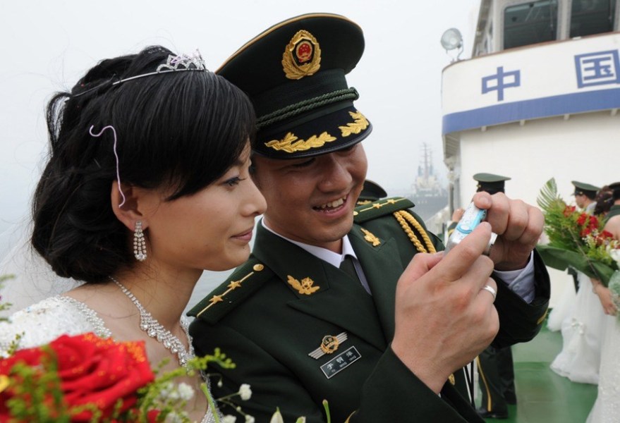 Le 29 juillet 2010 à Qinhuangdao au Hebei, un couple regarde leurs photos prises lors d'un mariage collectif. 